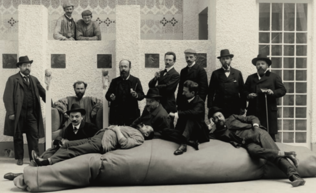 Moriz Nähr: Foto di gruppo con gli artisti della cosiddetta “Mostra di Beethoven” nella sala centrale del Palazzo della Secessione a Vienna; nella fila davanti, da sinistra a destra: Kolo Moser, Maximilian Lenz, Ernst Stöhr, Emil Orlik, Carl Moll; nella fila dietro da sinistra a destra: Anton Nowak, Gustav Klimt, Adolf BöhmKlimt Foundation, Vienna © Klimt Foundation, Vienna